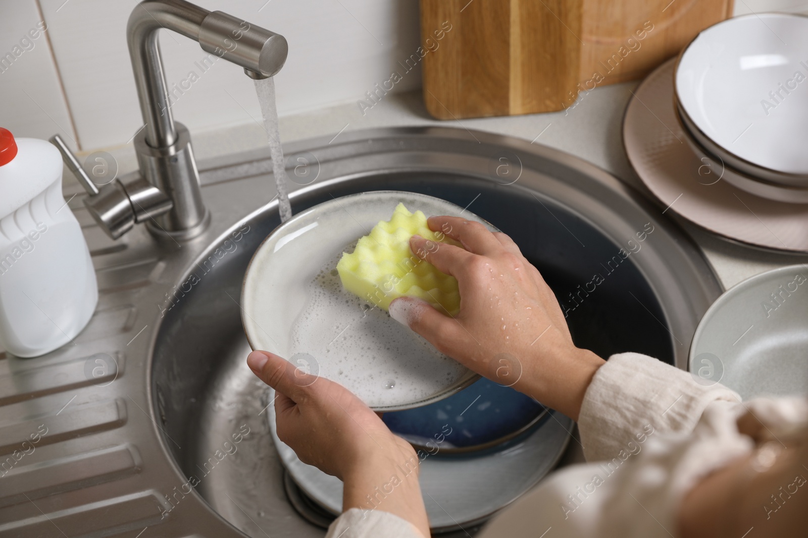 Photo of Woman washing plate in kitchen sink, above view