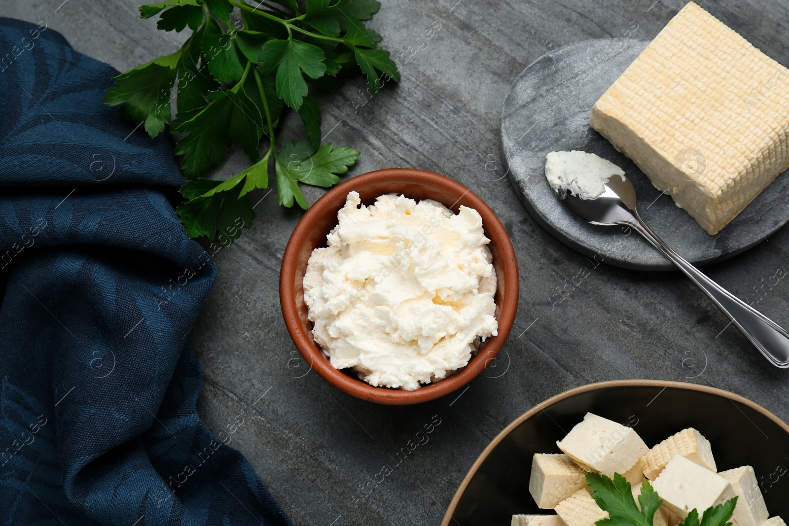 Photo of Delicious tofu cheese and parsley on black table, flat lay