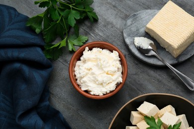 Photo of Delicious tofu cheese and parsley on black table, flat lay