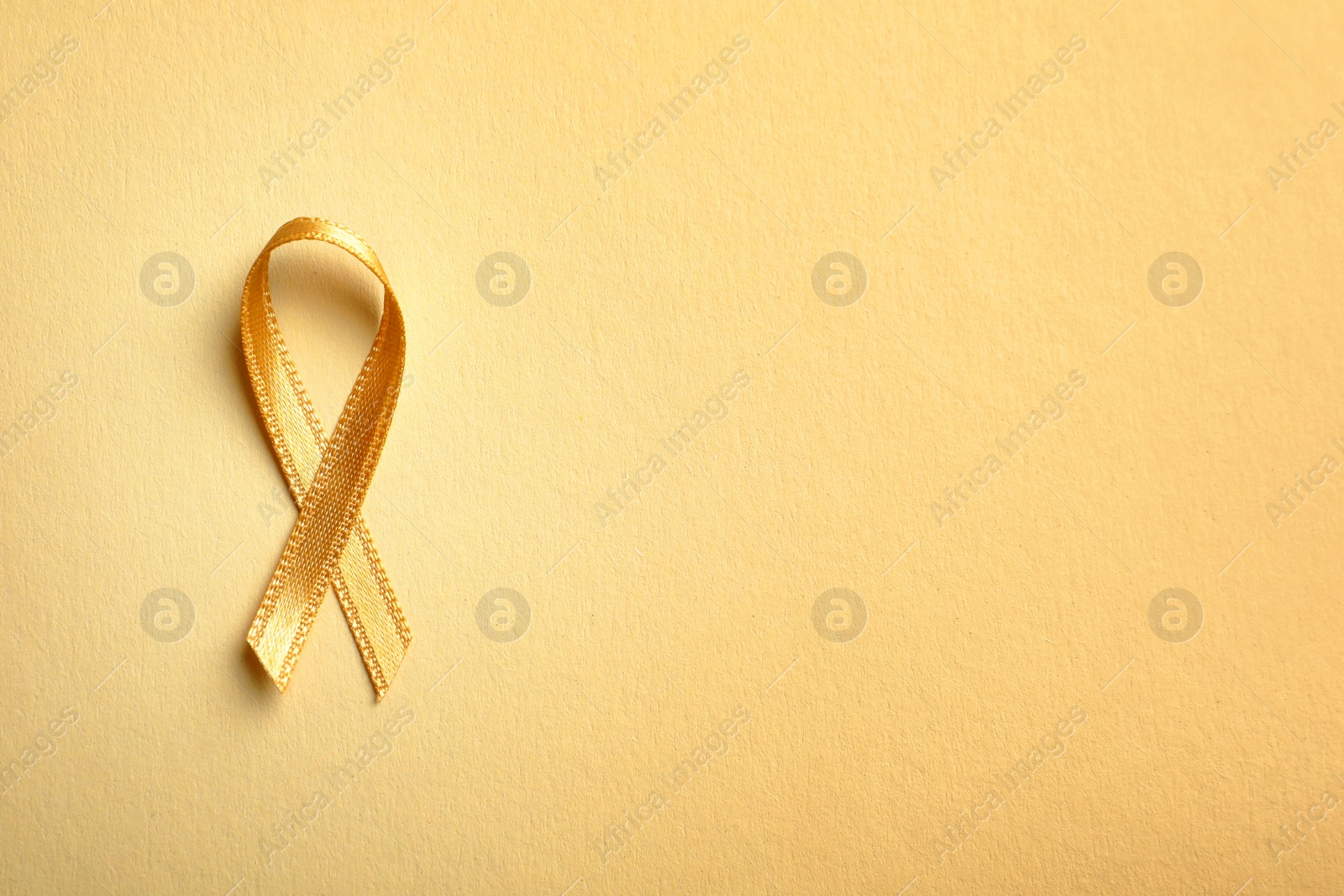 Photo of Gold ribbon on color background, top view. Cancer awareness