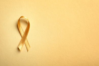 Gold ribbon on color background, top view. Cancer awareness