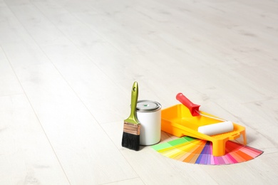 Photo of Can of paint and decorator tools on wooden floor indoors. Space for text
