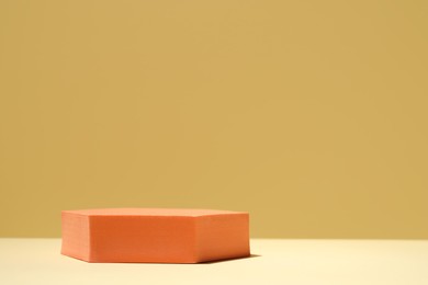 Photo of Orange stand on table against yellow background, space for text. Stylish presentation for product