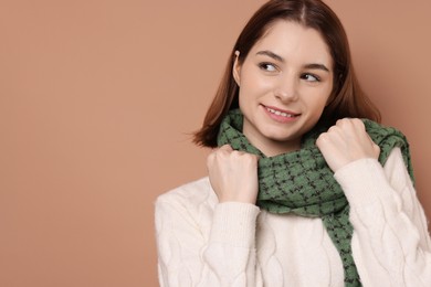 Photo of Beautiful woman in warm scarf on brown background, space for text