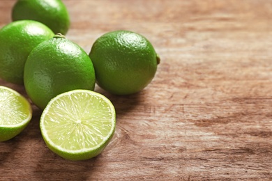 Photo of Fresh ripe limes on wooden table. Citrus fruit