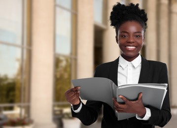 Image of Lawyer, consultant, business owner. Confident woman with file folders smiling outdoors, space for text