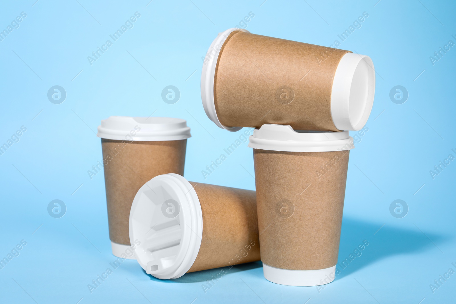 Photo of Paper cups with white lids on light blue background. Coffee to go