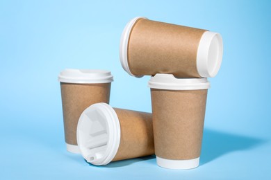 Paper cups with white lids on light blue background. Coffee to go