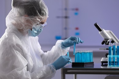 Scientist holding test tubes with light blue liquid in laboratory