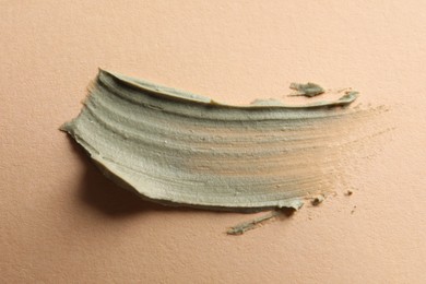 Photo of Sample of face cream on pale orange background, top view