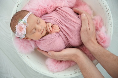 Photo of Cute newborn baby girl with her father on light background, top view