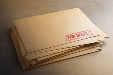 Image of Top Secret stamp. Stacked paper envelopes on table