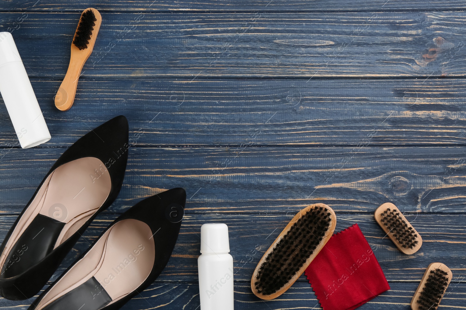 Photo of Stylish footwear with shoe care accessories on blue wooden table, flat lay. Space for text