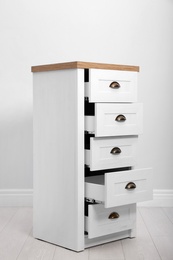 Photo of Stylish chest of drawers near white wall. Furniture for wardrobe room