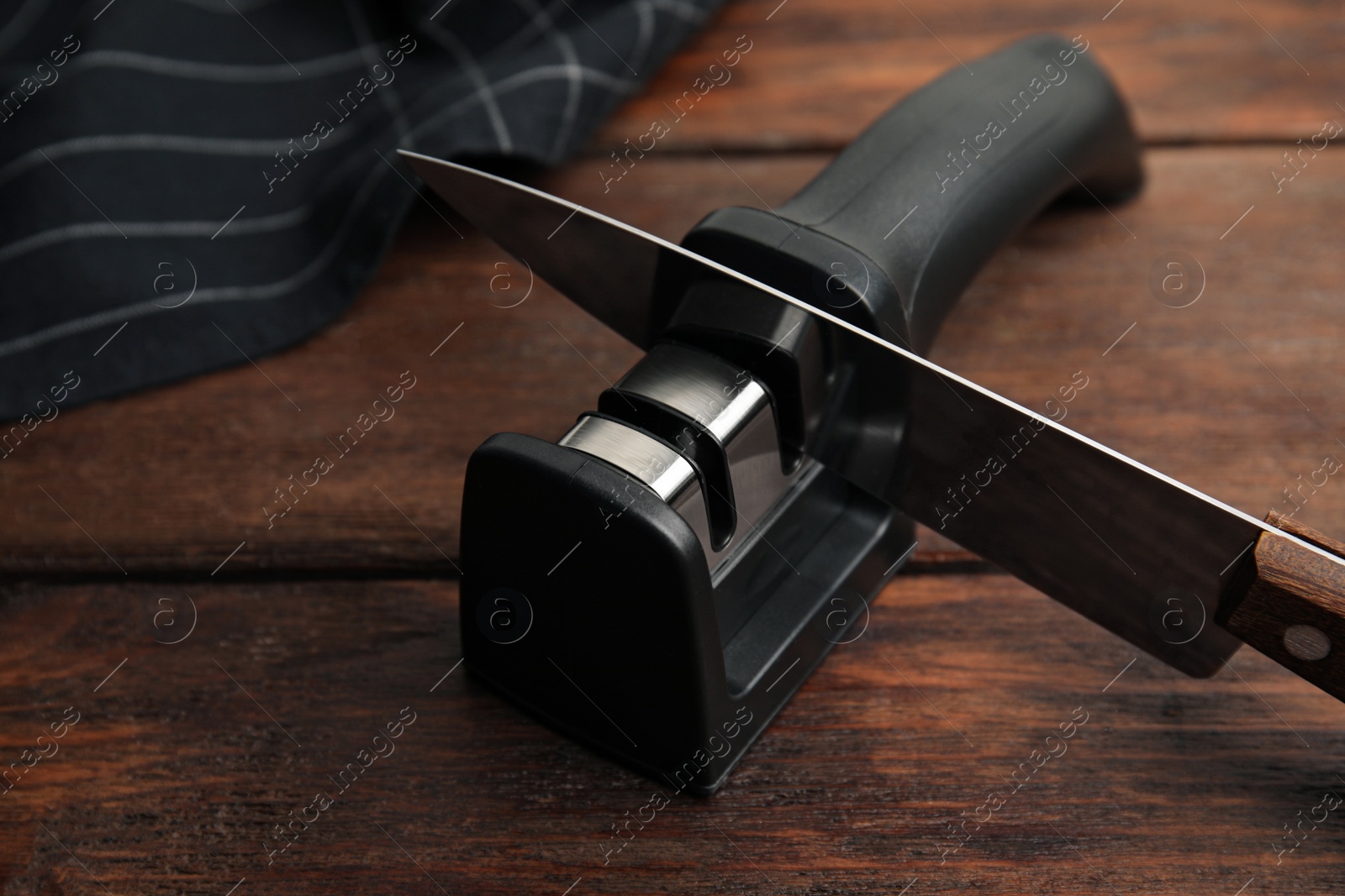 Photo of Modern handheld sharpener and knife on wooden table