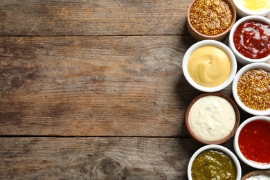 Photo of Set of different delicious sauces on wooden table, top view. Space for text