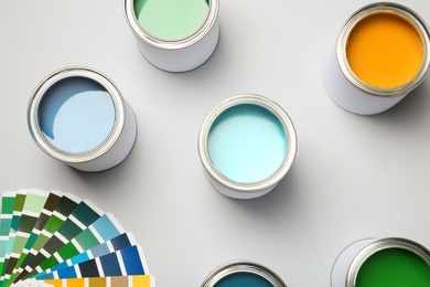 Paint cans and color palette on white background, top view