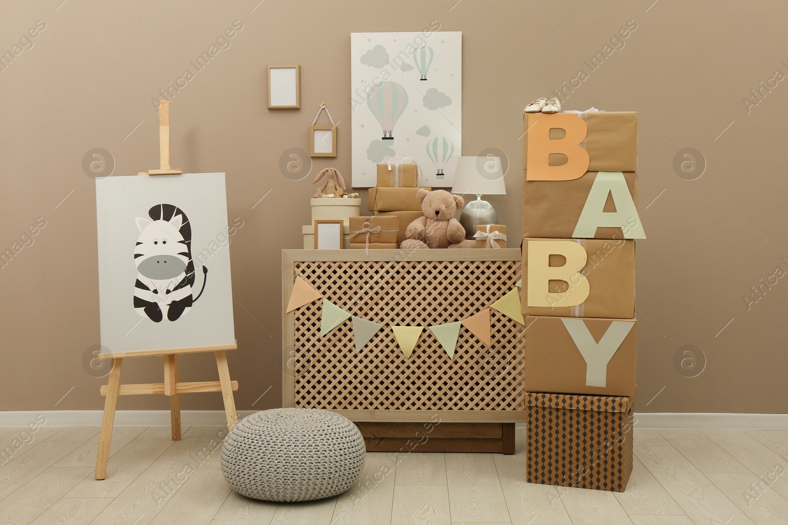 Photo of Easel with painting and gift boxes in room decorated for baby shower party