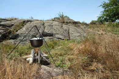 Photo of Cauldron above dry firewood arranged for bonfire outdoors. Camping season