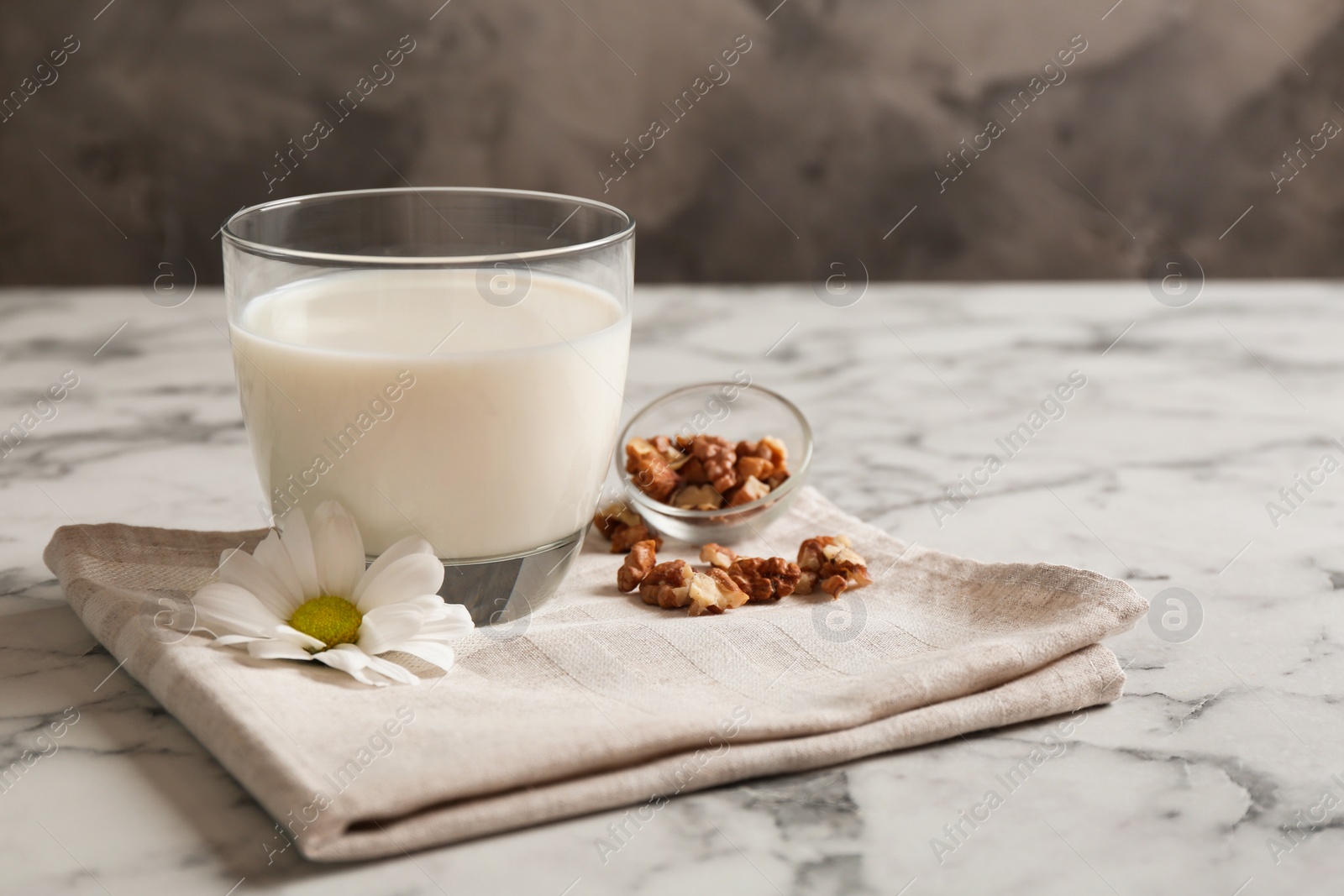 Photo of Glass with milk and nuts on table