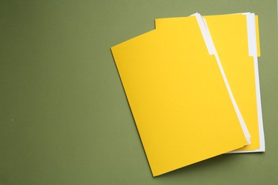 Photo of Yellow files with documents on olive background, top view. Space for text
