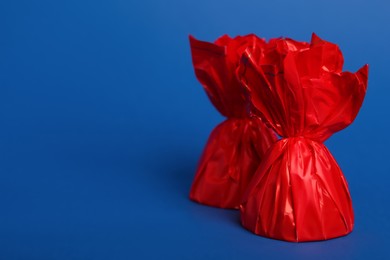 Photo of Candies in red wrappers on blue background. Space for text