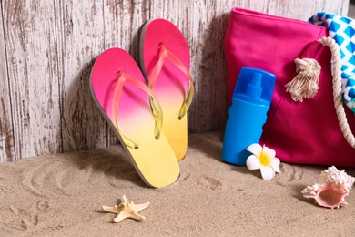 Photo of Composition with stylish summer beach accessories on sand near wooden wall