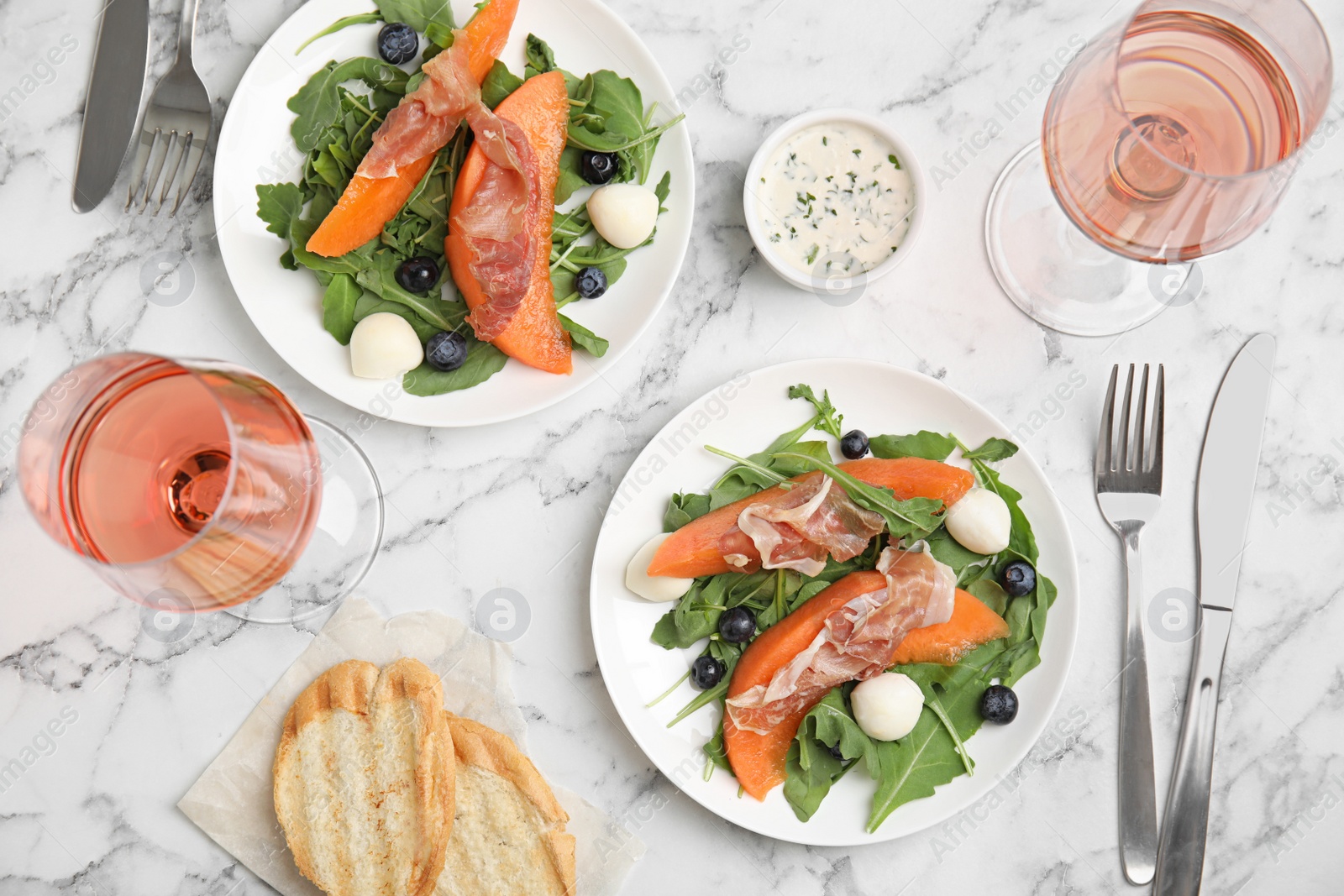 Photo of Flat lay composition of fresh melon with prosciutto on marble table