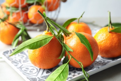 Plate with tasty ripe tangerines on table