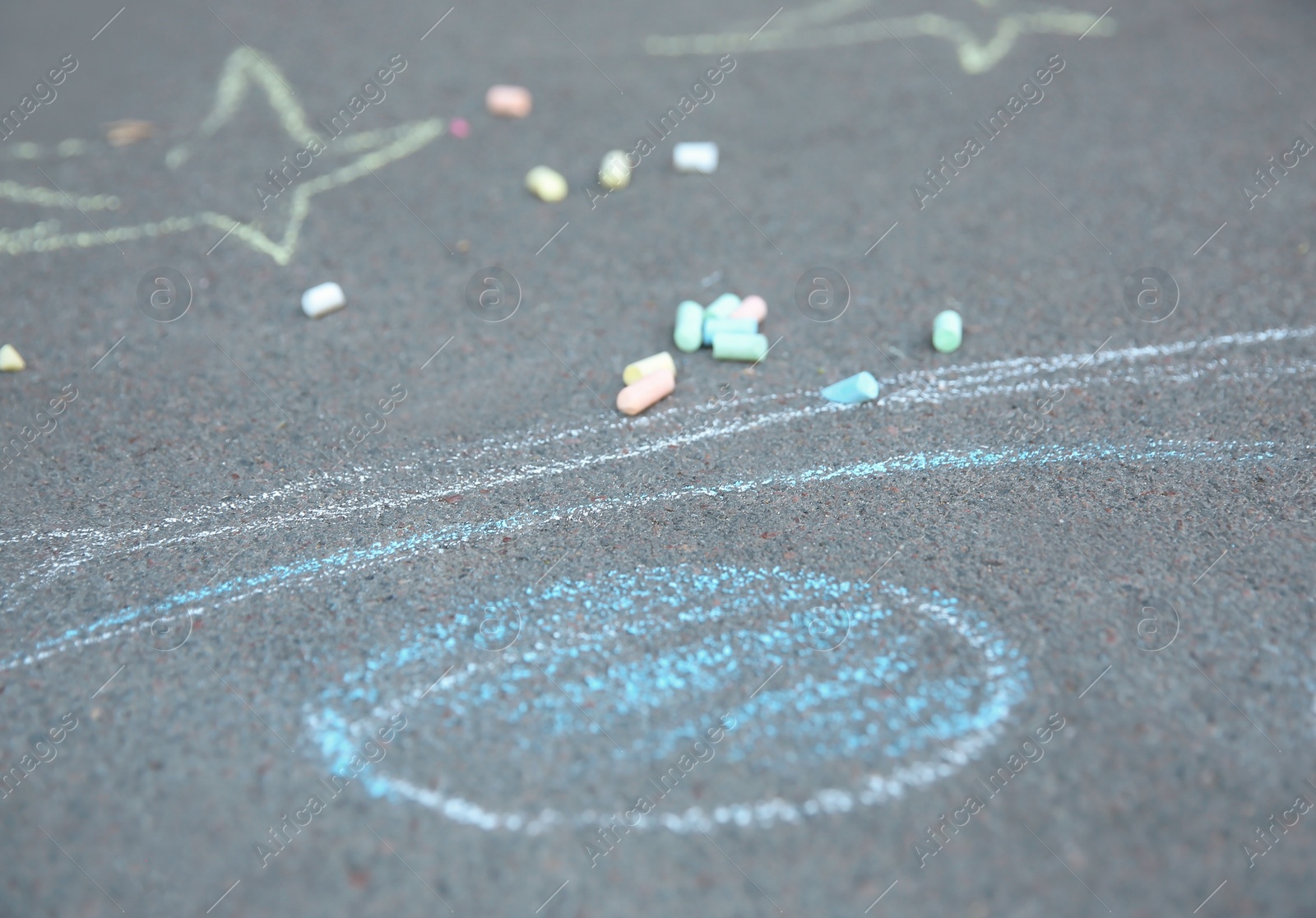 Photo of Pieces of chalk and child's drawing on asphalt sidewalk, closeup