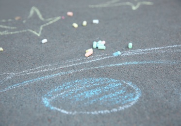 Photo of Pieces of chalk and child's drawing on asphalt sidewalk, closeup