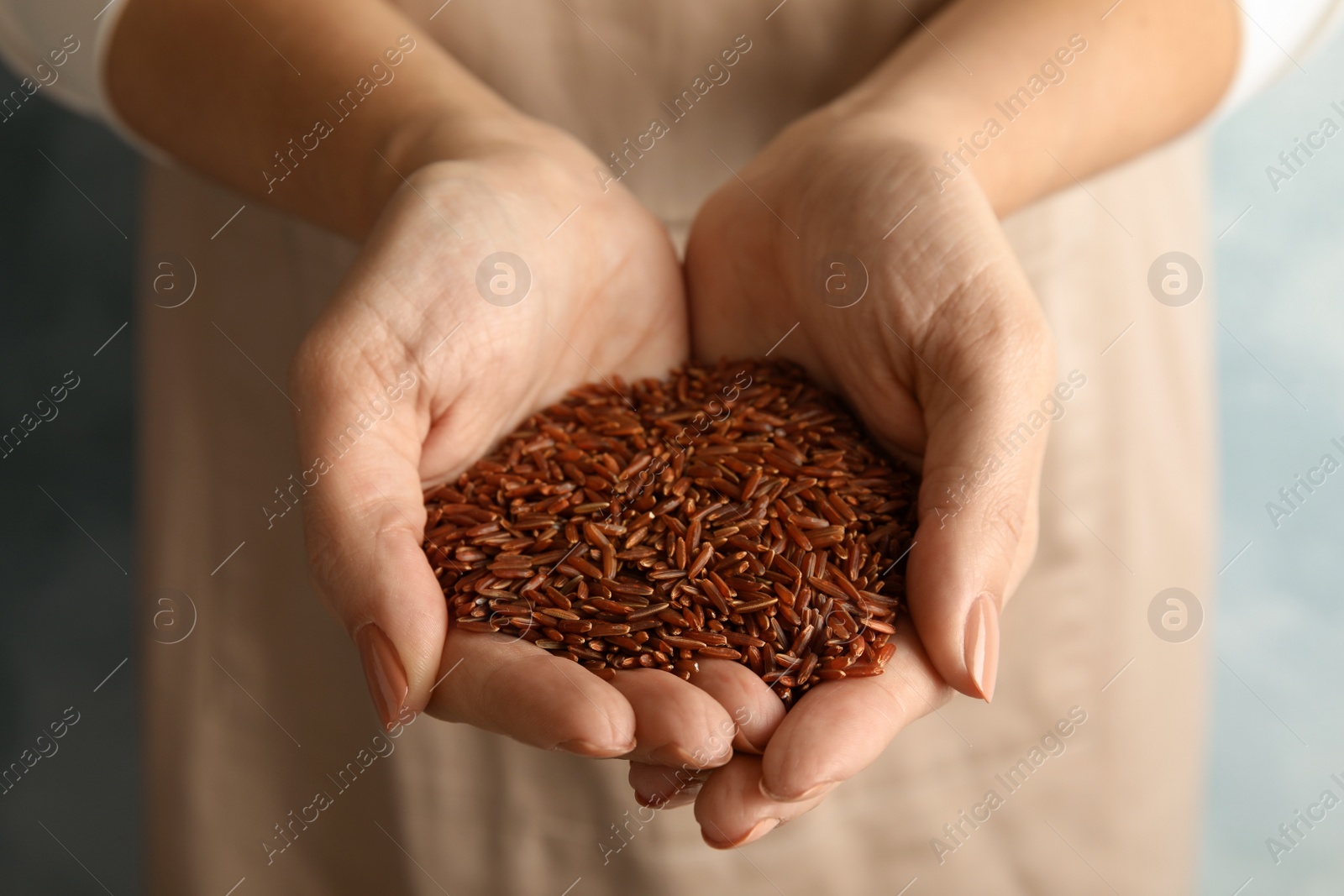 Photo of Woman with hands full of uncooked red rice, closeup