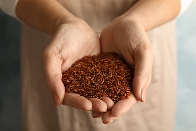 Woman with hands full of uncooked red rice, closeup