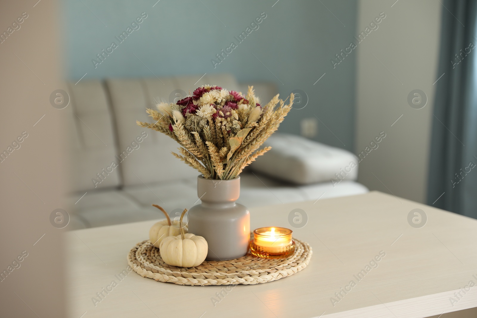 Photo of Beautiful bouquet of dry flowers, small pumpkins and candle on white table indoors