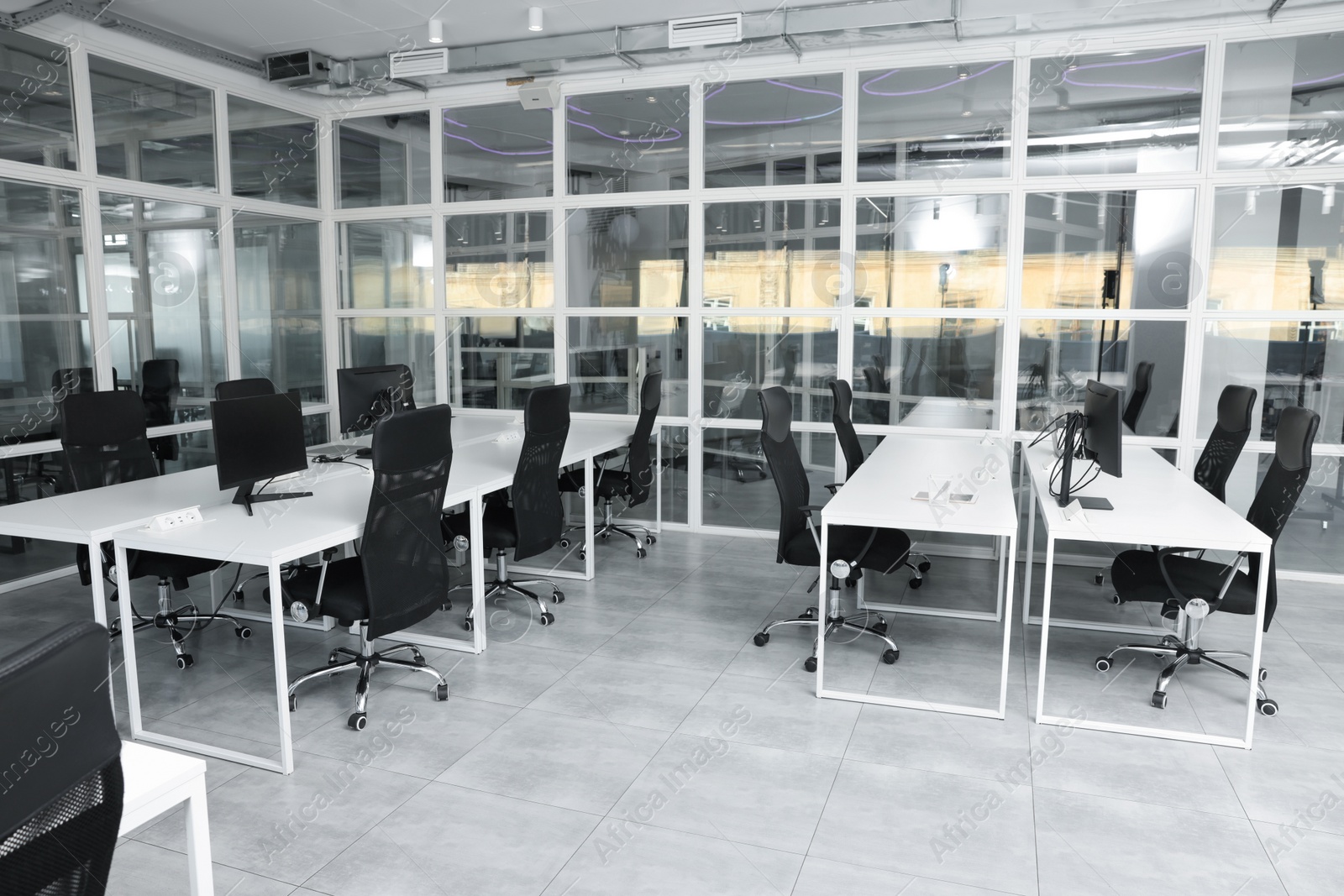 Photo of Stylish interior of open plan office. Workspace with computers, tables and chairs