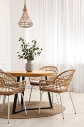 Photo of Dining room interior with comfortable furniture and eucalyptus branches