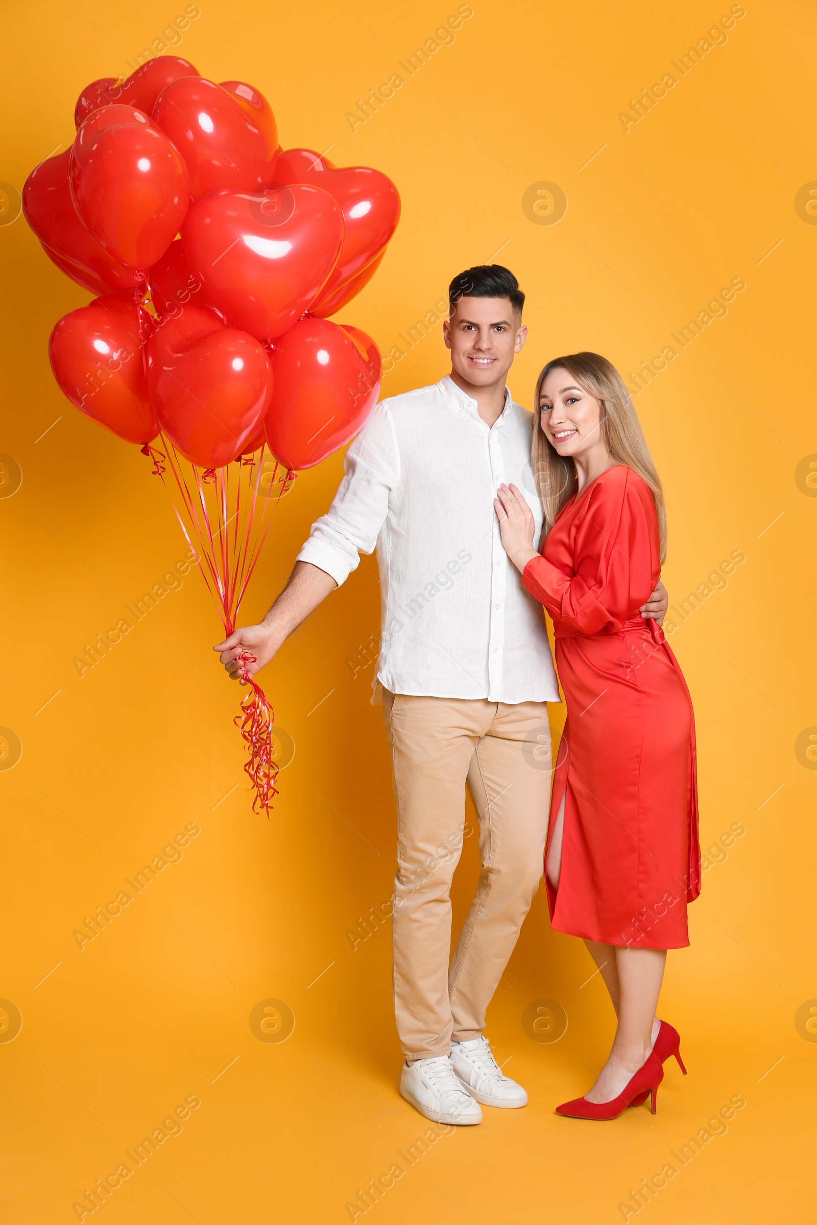 Photo of Lovely couple with heart shaped balloons on yellow  background. Valentine's day celebration