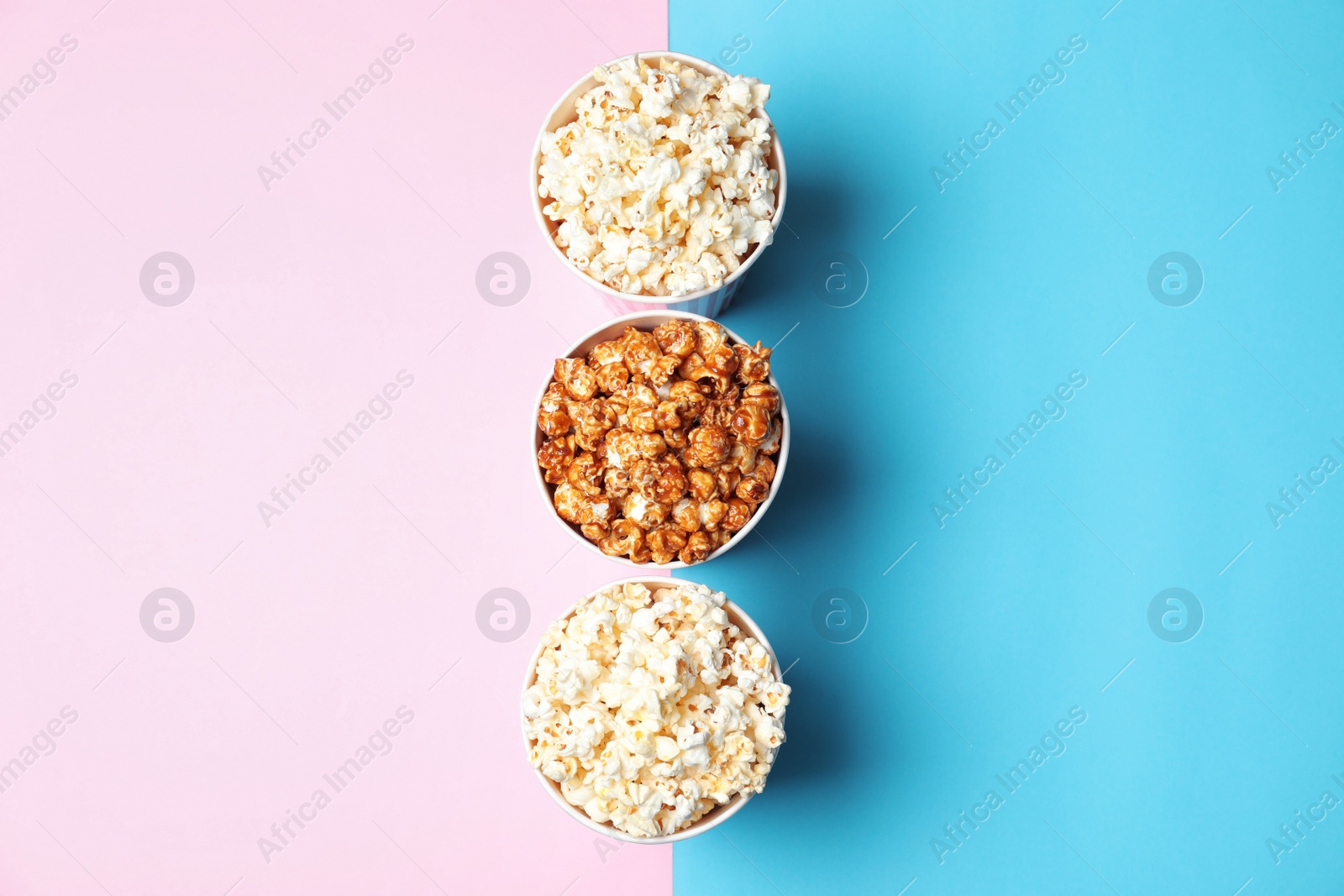 Photo of Different kinds of popcorn in paper cups on color background, top view