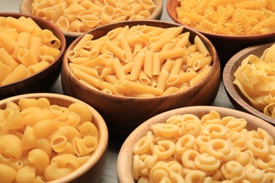 Photo of Different types of pasta in bowls on table, closeup