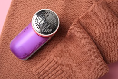 Photo of Modern fabric shaver and sweater with lint on pink background, top view
