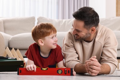 Photo of Father and son with bubble level at home. Repair work