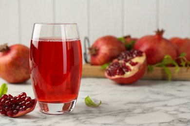 Photo of Tasty pomegranate juice in glass and fresh fruits on white marble table. Space for text