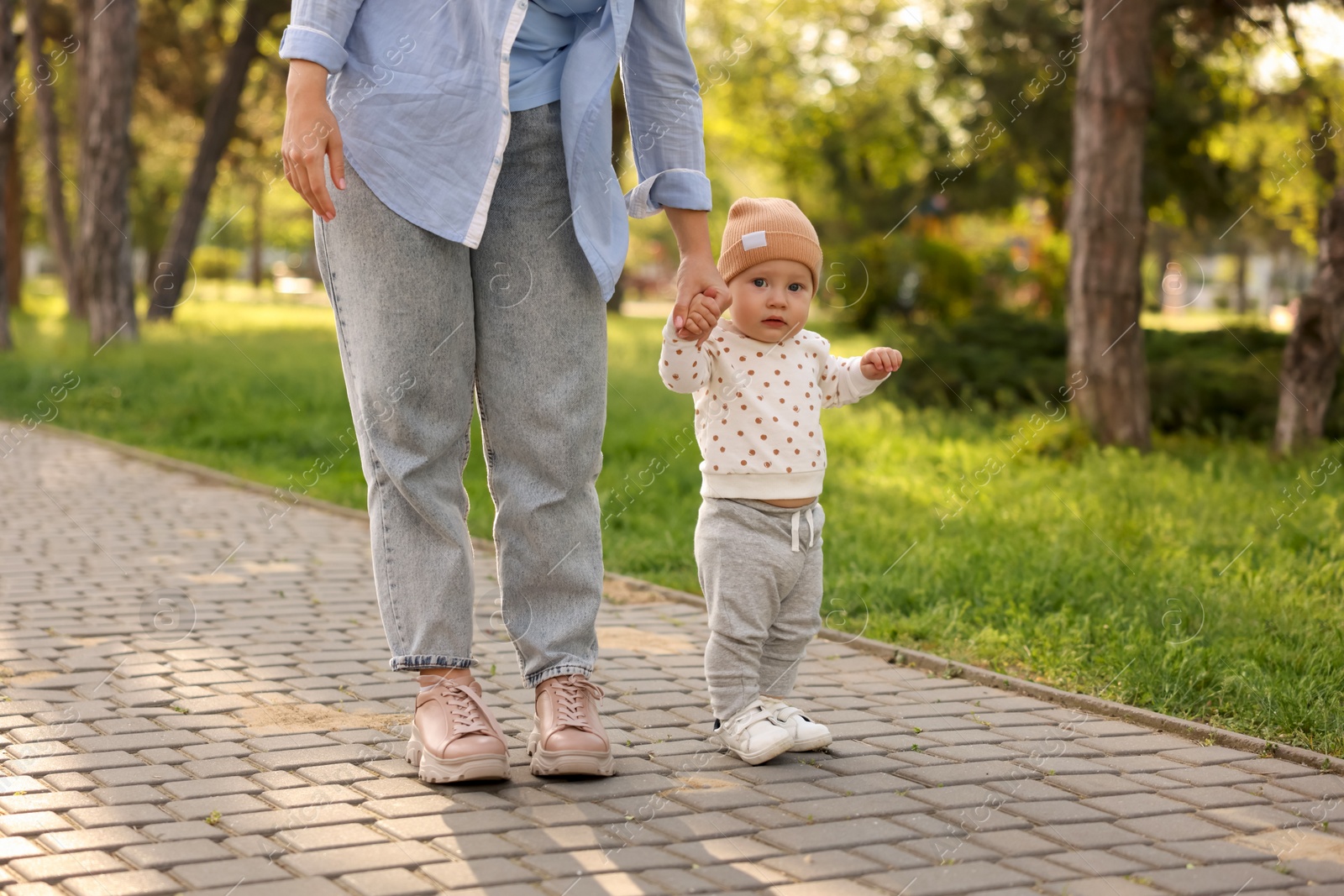 Photo of Mother supporting her baby while he learning to walk outdoors, closeup