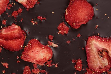 Photo of Chocolate bar with freeze dried strawberries as background, closeup