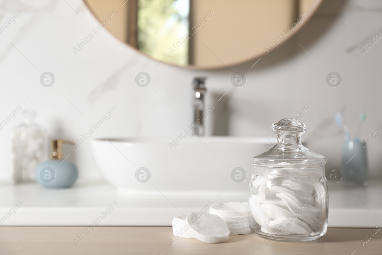 Photo of Cotton pads on wooden table in bathroom