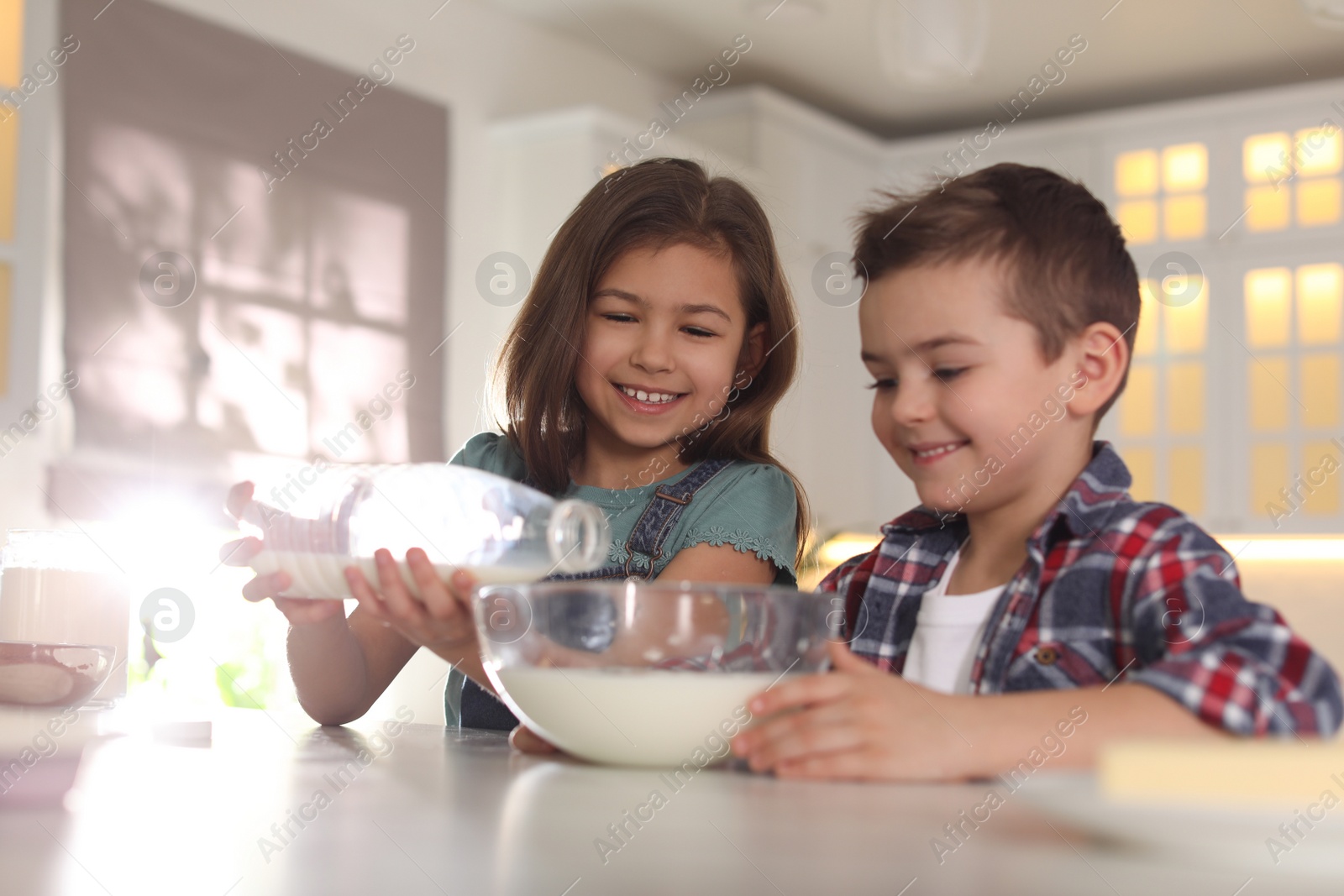 Photo of Cute little children cooking dough in kitchen at home