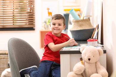 Little child painting at table in room