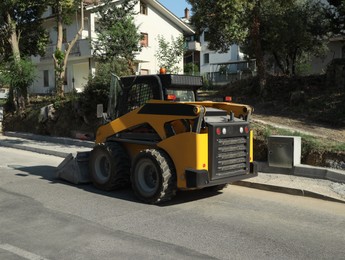 Photo of Modern skid loader on city street. Road repair