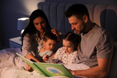 Photo of Family reading book together in bed at home