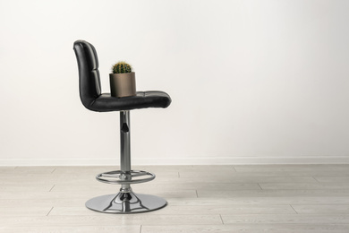 Chair with cactus near white wall, space for text. Hemorrhoids concept